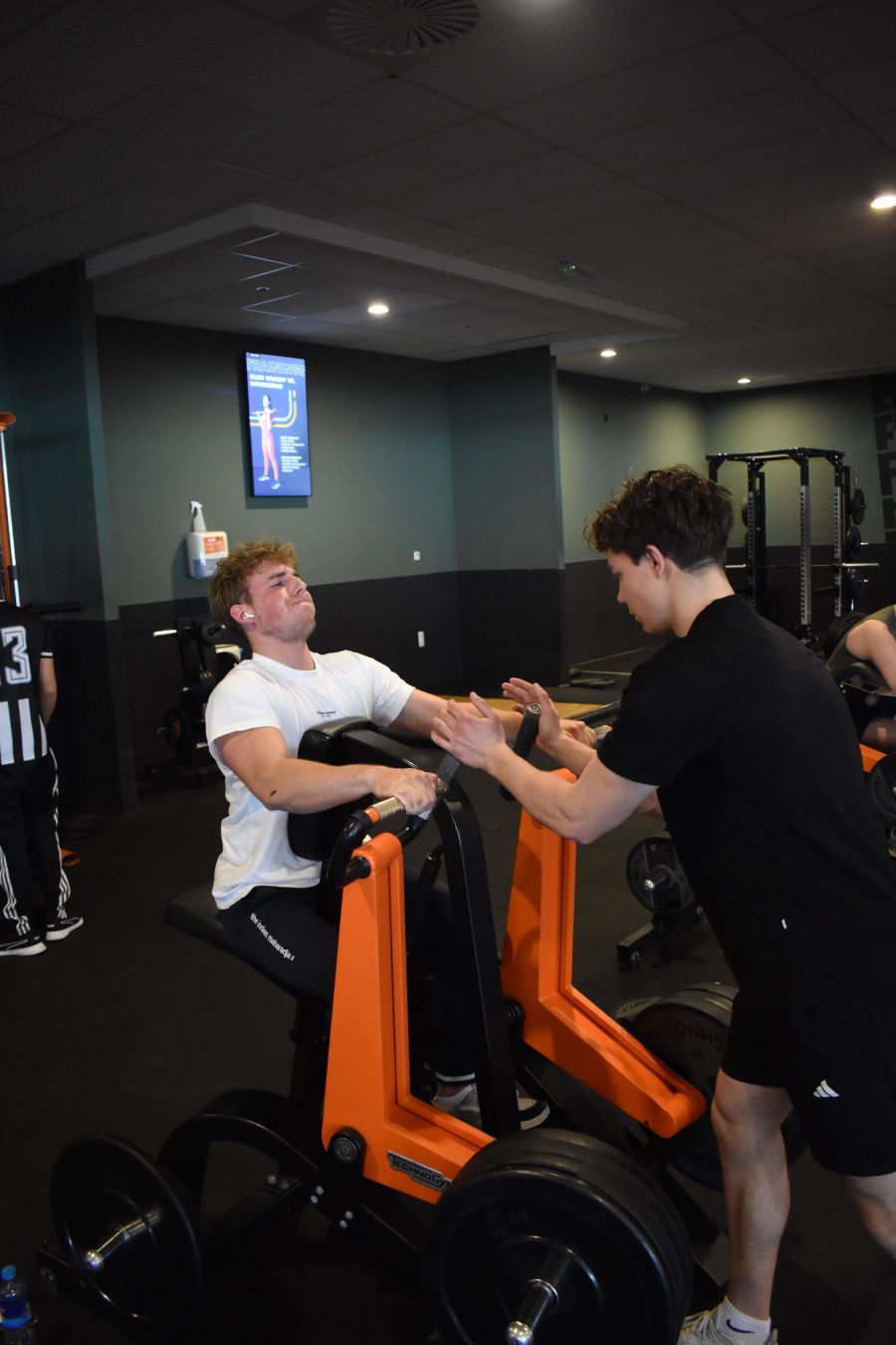Jason begeleidt een klant bij biceps curls op de preacher curl-bank